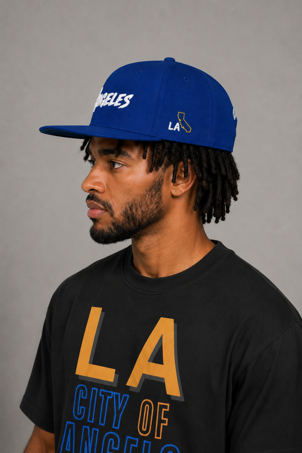Los Angeles City of Angels Royal Blue Embroidered Snapback Hat — close-up model profile showing gold California state outline and white LA side embroidery | City 2 City Wear
