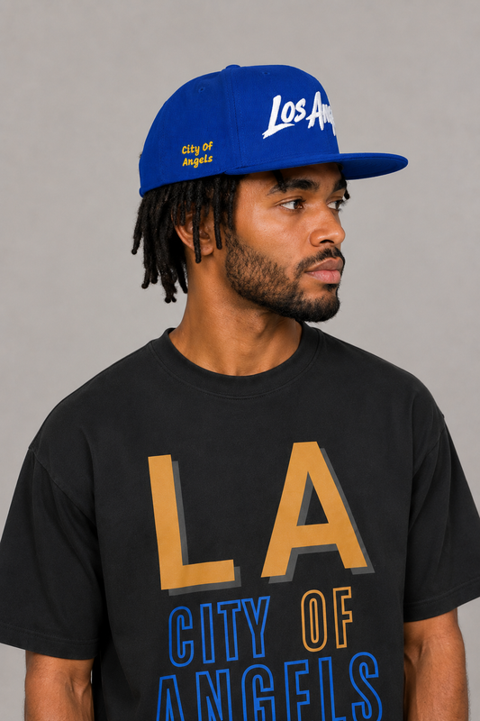 Los Angeles City of Angels Royal Blue Embroidered Snapback Hat — close-up model profile showing gold City of Angels side embroidery and white Los Angeles front script | City 2 City Wear