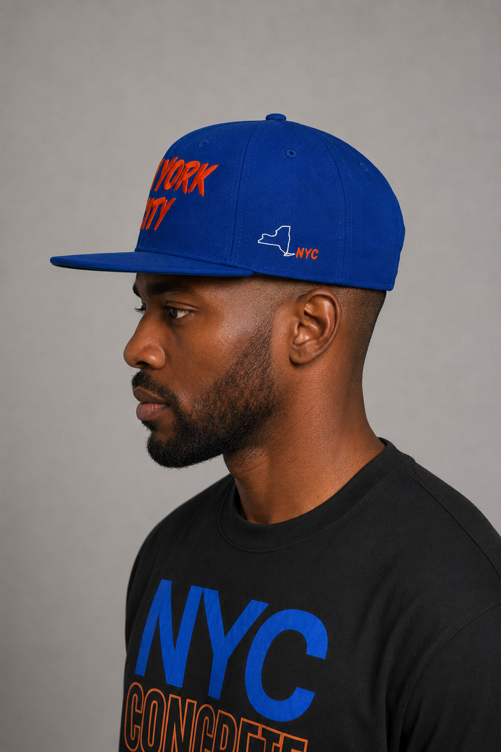 NYC Concrete Jungle Royal Blue Embroidered Snapback Hat — close-up left-side model profile showing white New York state outline and orange-red NYC embroidery | City 2 City Wear