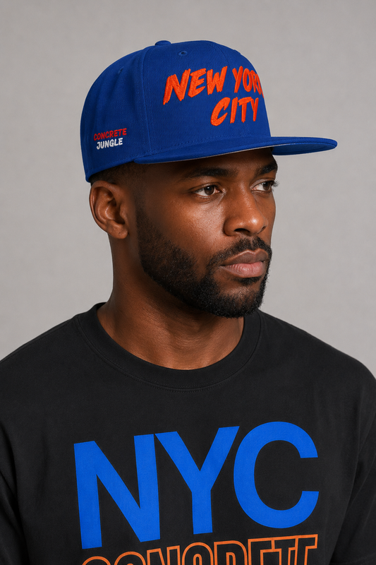 NYC Concrete Jungle Royal Blue Embroidered Snapback Hat — close-up New York City model profile showing CONCRETE JUNGLE side embroidery, flat brim, and orange-red NEW YORK CITY front lettering | City 2 City Wear